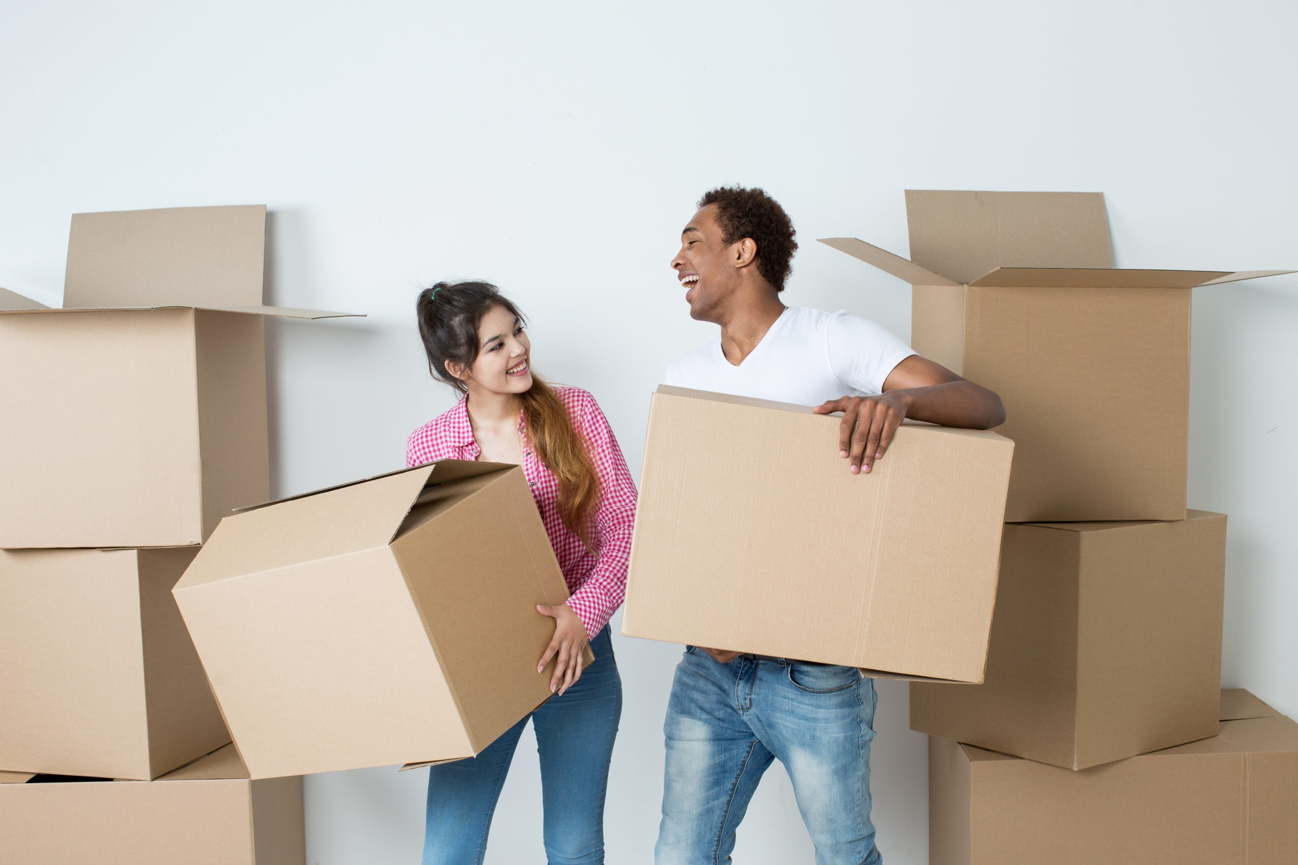 Smiling couple carrying moving boxes together before a home move