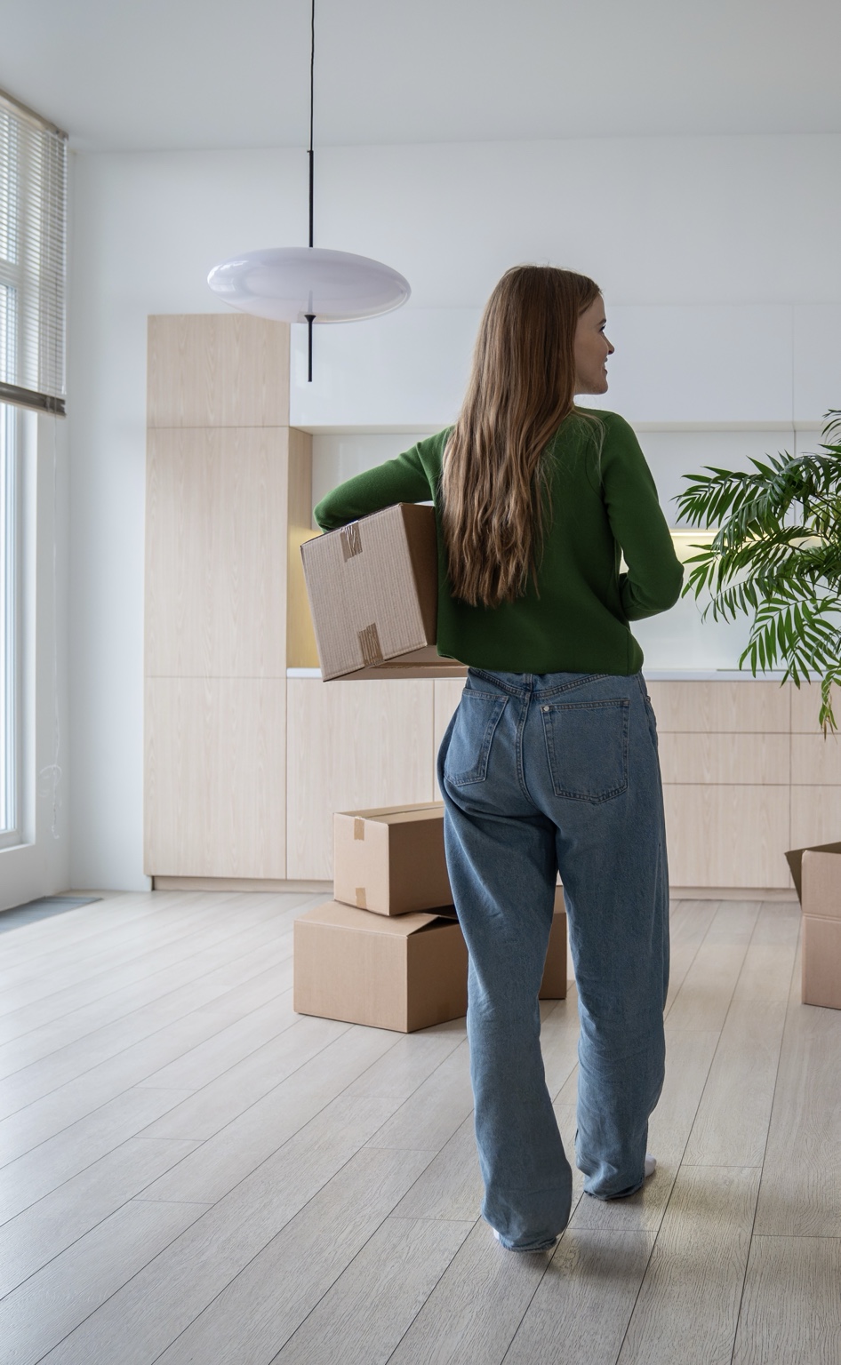 Woman carrying a moving box into a bright new home